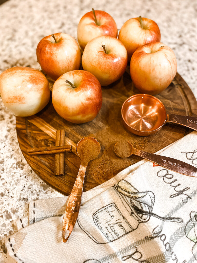 Apples and spices on a cutting board with a tea towel.
