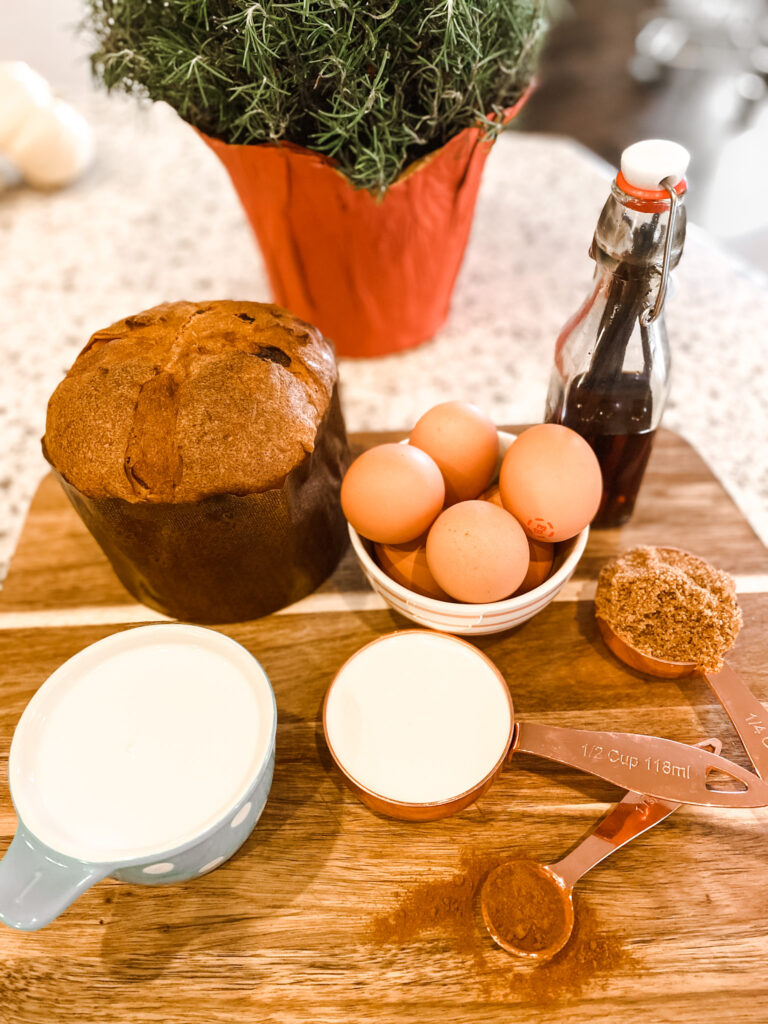 Panettone, eggs, milk, heavy cream, cinnamon, brown sugar, and vanilla on a cutting board. 