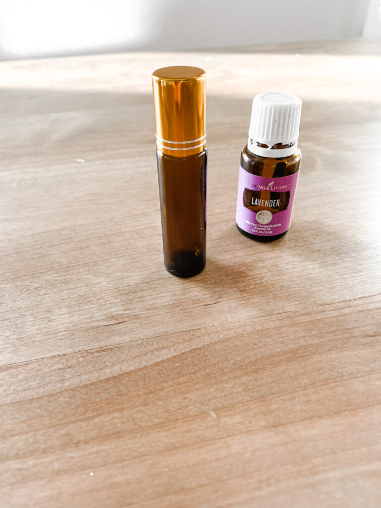 Essential oil roller ball next to lavender essential oil on a wooden table. 