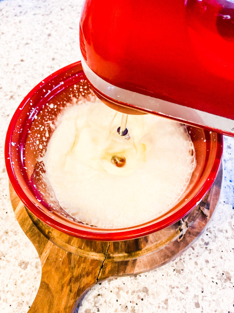 Heavy cream in a red bowl with a mixer