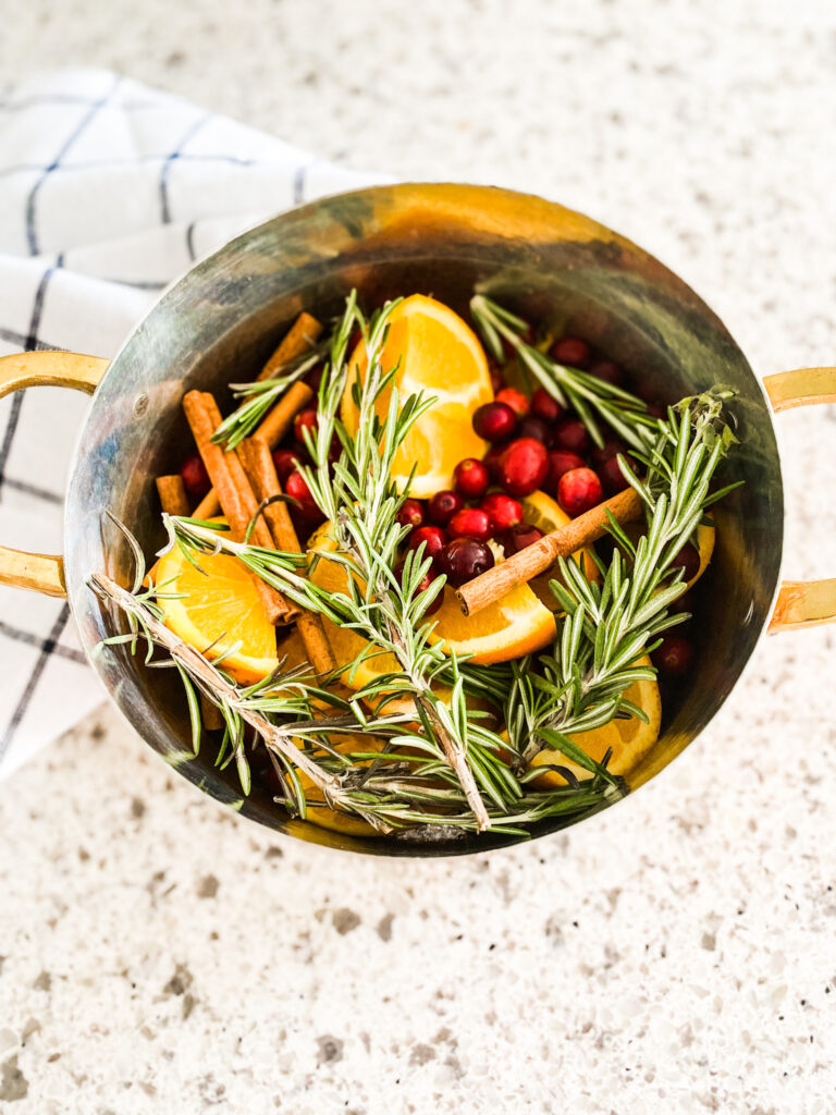 Orange slices, cranberries, and cinnamon sticks  and rosemary in a pot 