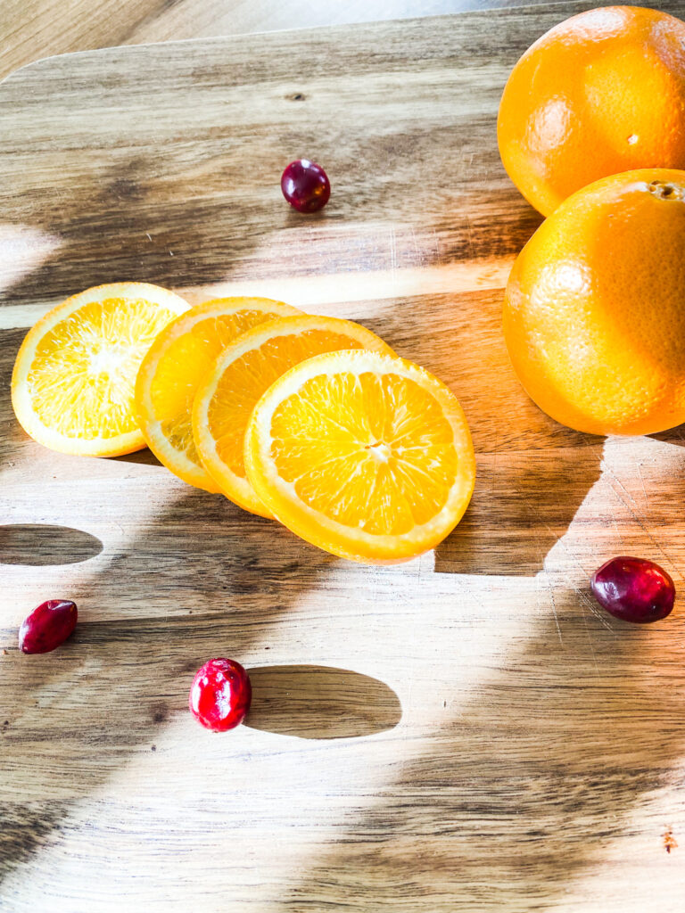 Cranberries and oranges on a wood cutting board. 