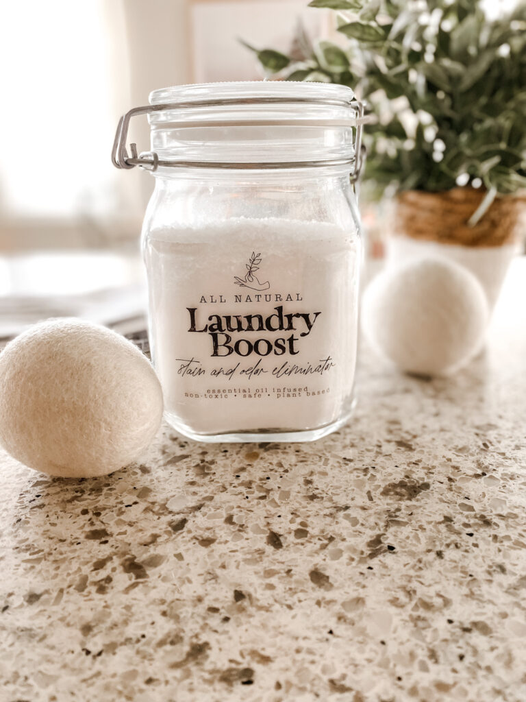 Jar of natural laundry scent boost with wool dryer balls on a counter. 