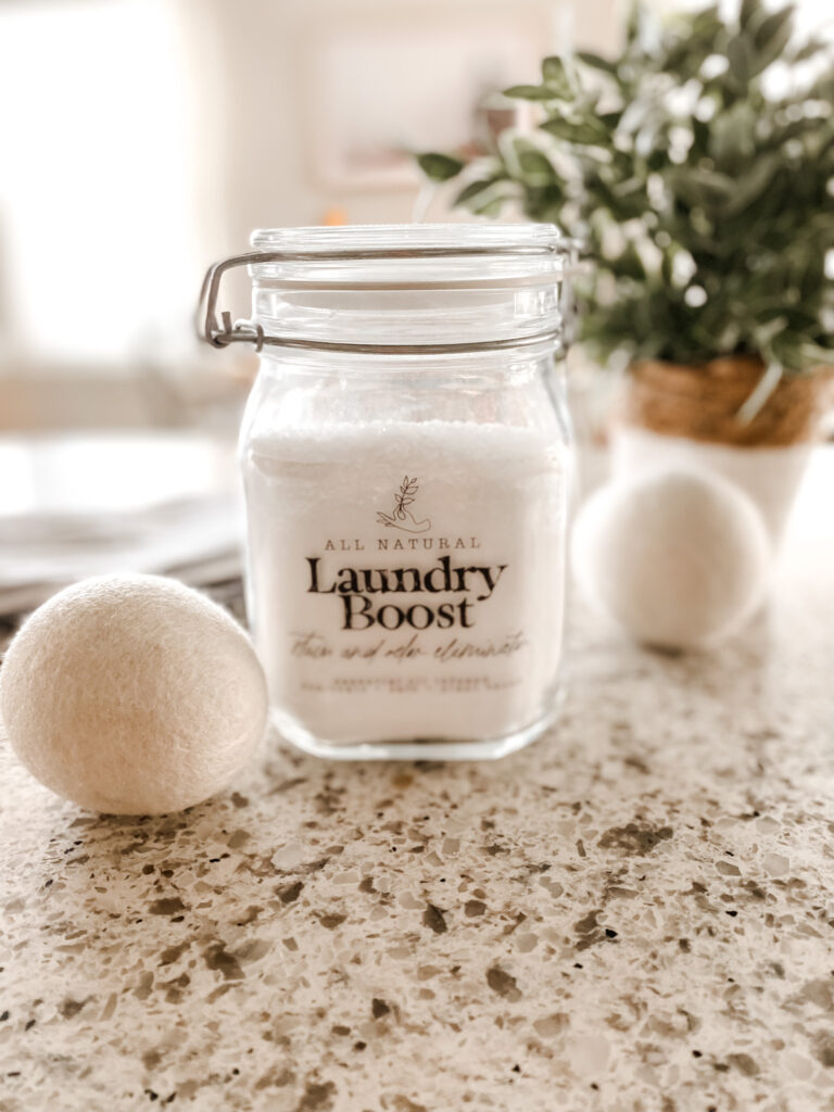 Jar of natural laundry scent boost with wool dryer balls on a counter. 
