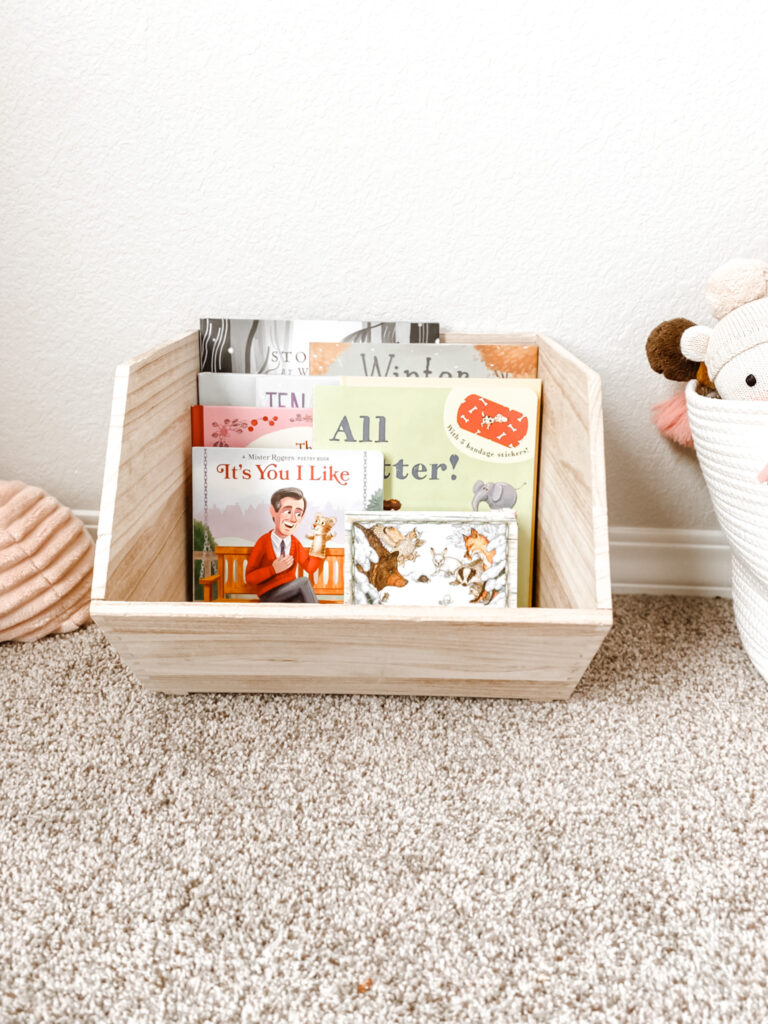 variety of kids books in a wooden bin