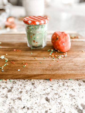 green and red homemade playdough on a wood cutting board in a jar