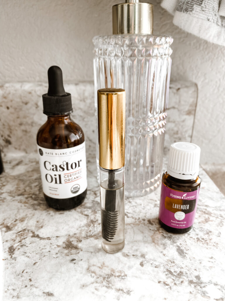 Castor oil, lash boot serum DIY, lavender oil and a crystal bottle on a counter 
