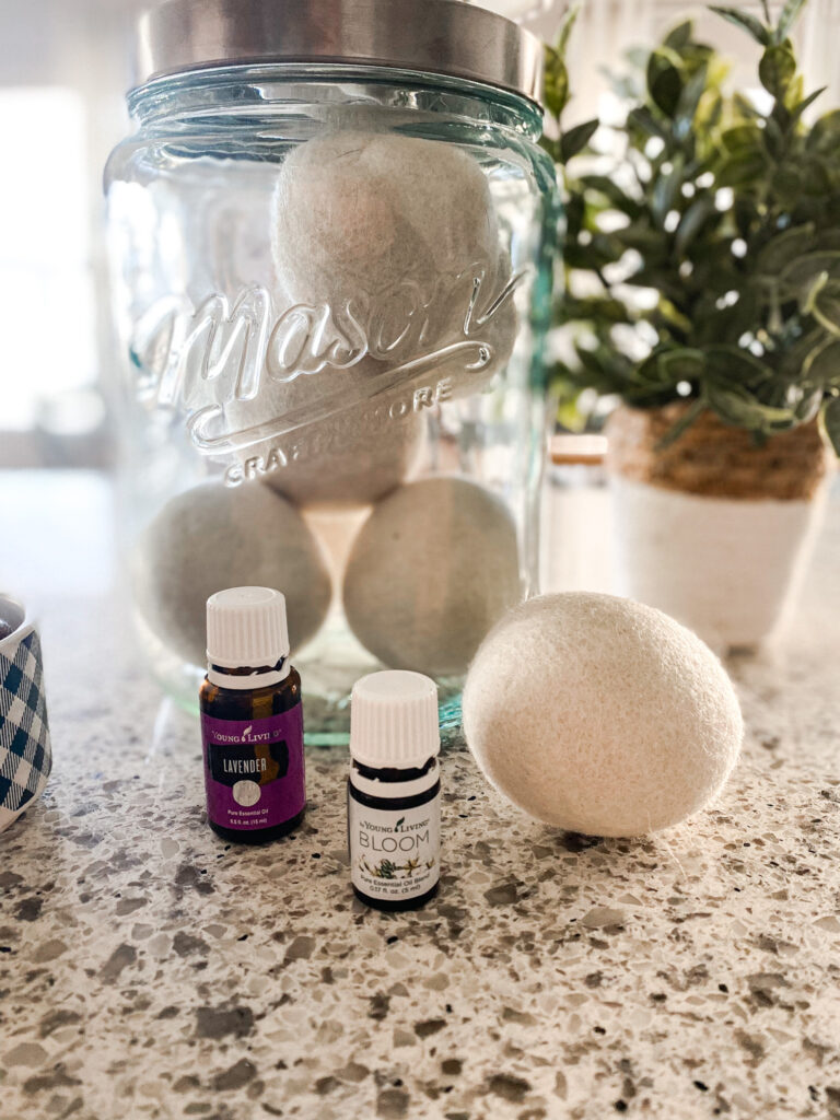 Lavender and bloom essential oil in front of a jar of wool dryer balls. 