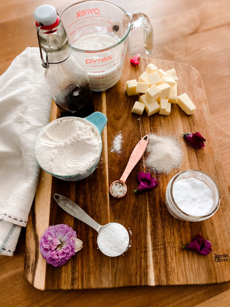 Flour, baking soda, baking powder, milk, and vanilla on a wood cutting board