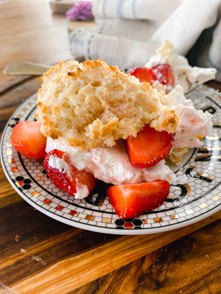 homemade strawberry shortcake on a black and white plate on a wood table