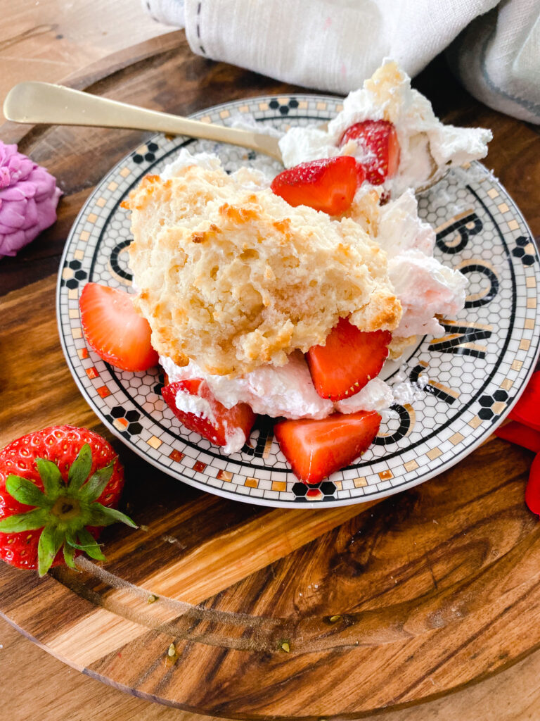 homemade strawberry shortcake on a black and white plate with a gold fork