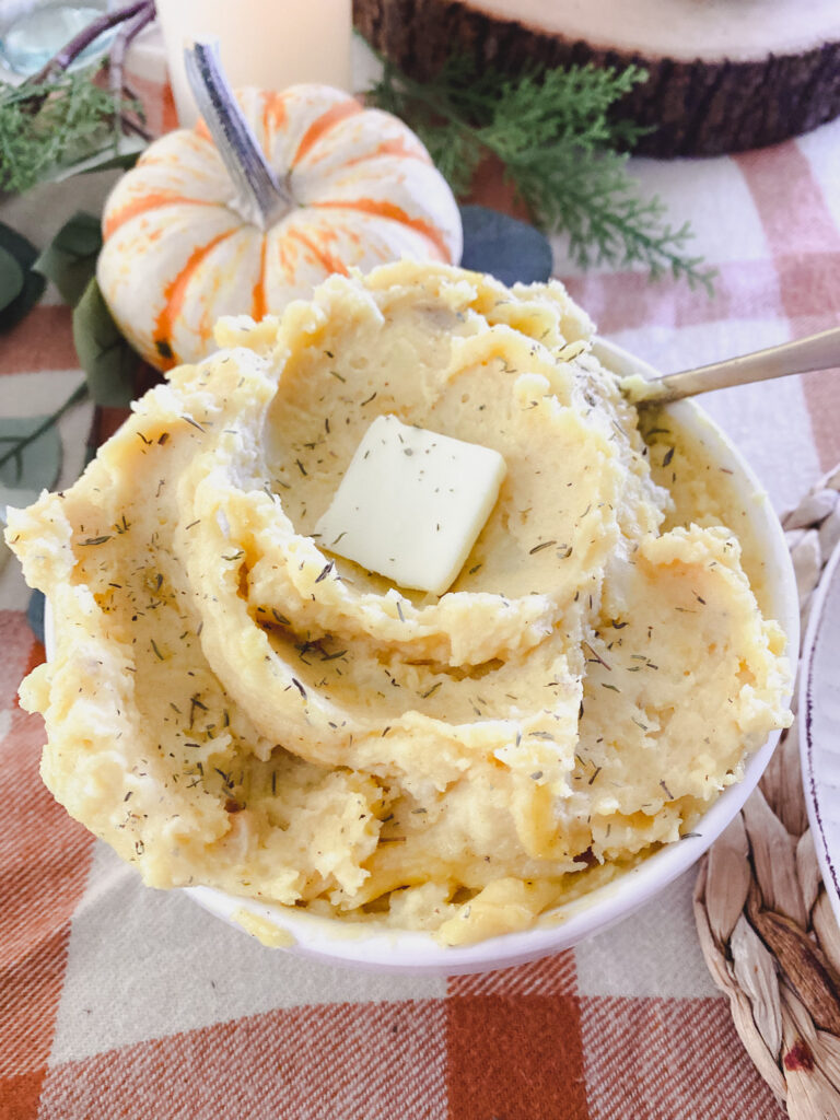 slow cooker mashed potatoes with brown butter in a bowl with a gold spoon. 