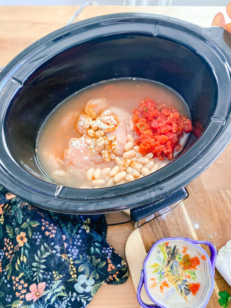 ranch chicken tortilla soup ingredients in a slow cooker on a table