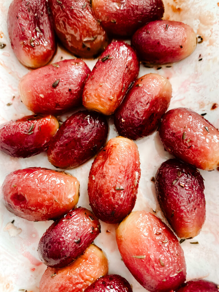 roasted grapes with olive oil and thyme on a white baking pan. 