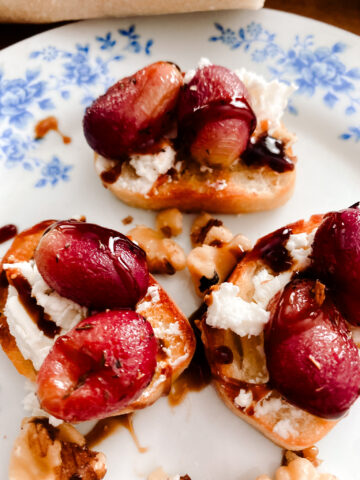 roasted grapes appetizer with walnuts and goat cheese on a blue and white floral plate